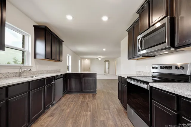 a kitchen with stainless steel appliances granite countertop wooden cabinets a stove top oven a sink and dishwasher