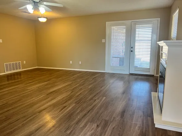 a view of an empty room with wooden floor and a window