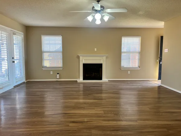 a view of an empty room with window and wooden floor