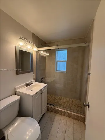 a bathroom with a sink a toilet a mirror and shower