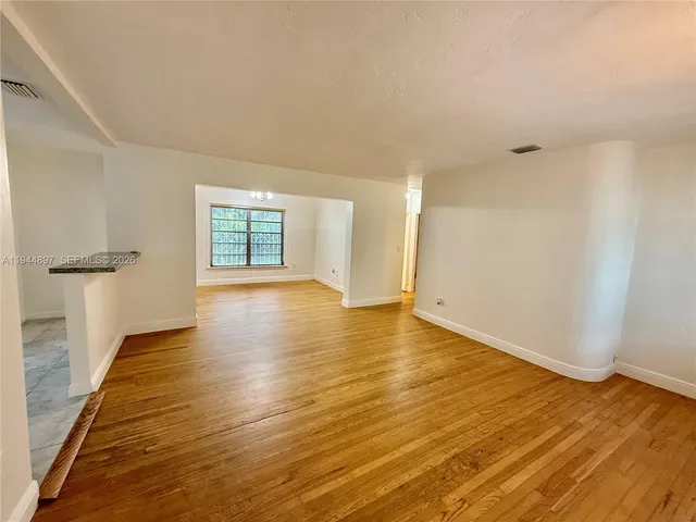 a view of a big room with wooden floor and windows