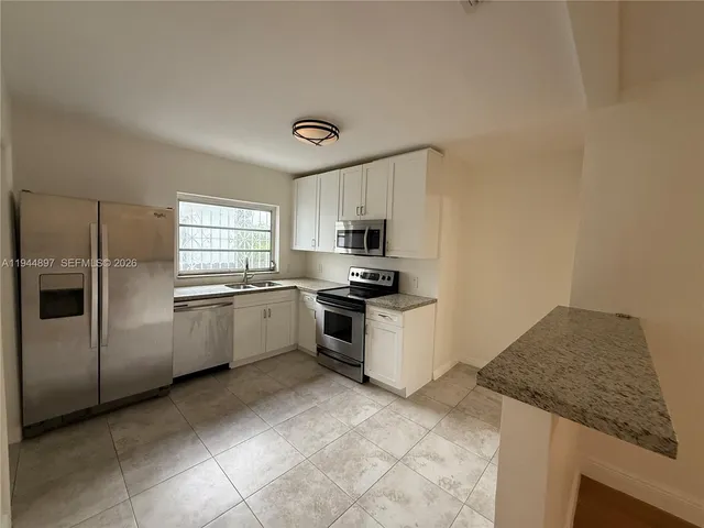 a kitchen with granite countertop a sink stainless steel appliances and cabinets