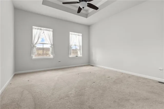 an empty room with windows and ceiling fan view