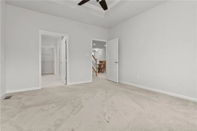 an empty room with chandelier fan and windows