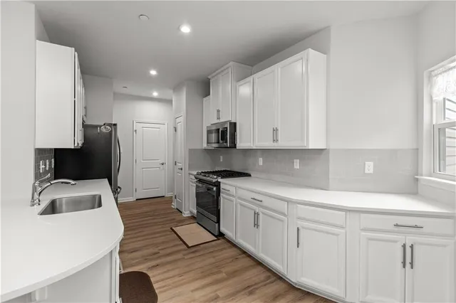 a kitchen with white cabinets sink and stainless steel appliances