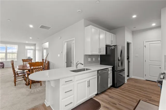 a kitchen with a sink a refrigerator and chairs