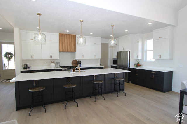 2201 East Unity Way Eagle Mountain, UT 84005 - Photo 12 of 39 Expansive kitchen featuring an oversized island with countertop seating, a two-tone cabinetry design, wood-finish flooring, and recessed lighting