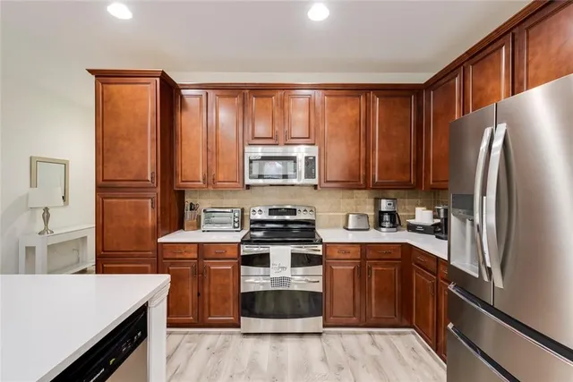 a kitchen with stainless steel appliances granite countertop a stove top oven a sink dishwasher and a refrigerator