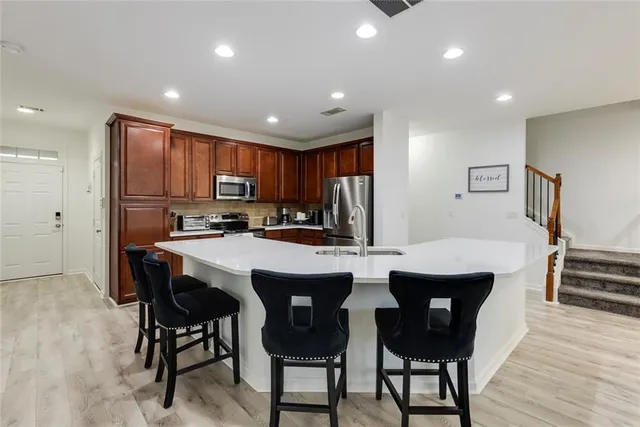 a kitchen with stainless steel appliances granite countertop a table chairs sink refrigerator and cabinets
