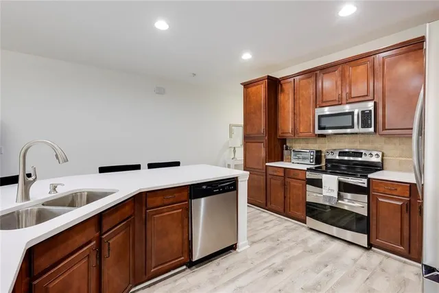 a kitchen with stainless steel appliances granite countertop a stove a sink dishwasher and a microwave oven with wooden floor