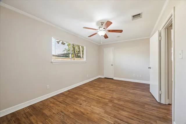 a view of an empty room with a window and wooden floor