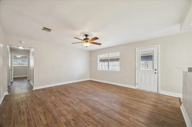 a view of an empty room with window and wooden floor