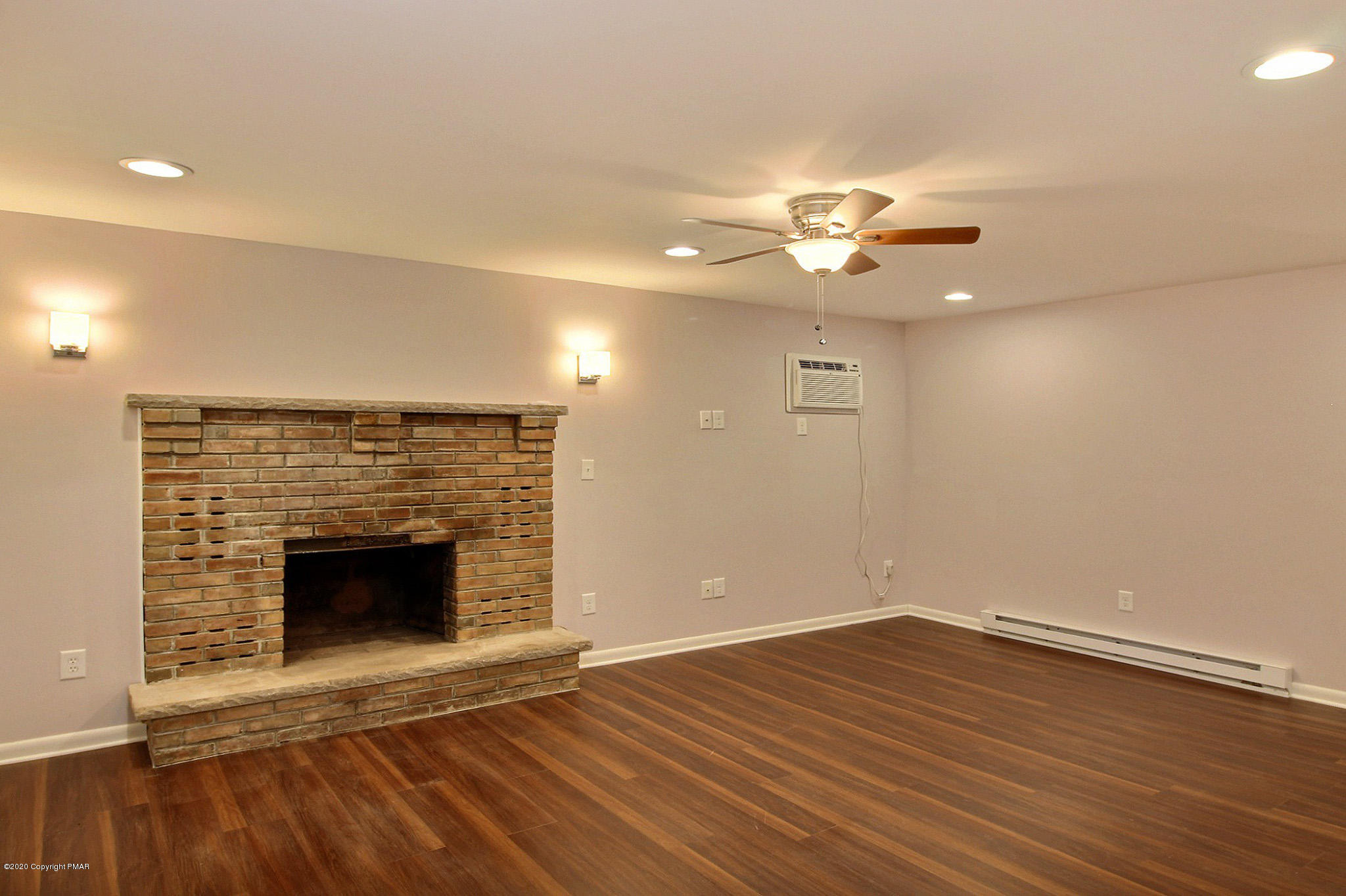 1191 Mattioli Road Bartonsville, PA 18321 - Photo 4 of 17 an empty room with wooden floor a chandelier fan and a fireplace