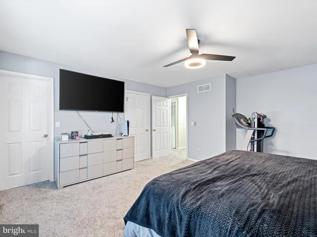 a bedroom with a bed and a flat tv screen on dresser
