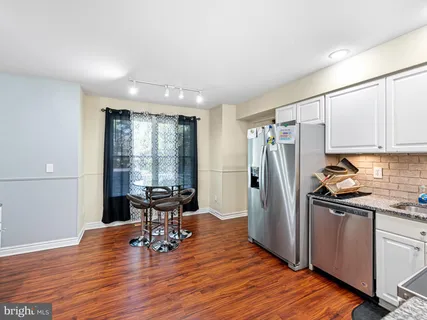 a kitchen with stainless steel appliances wooden floor and dining table