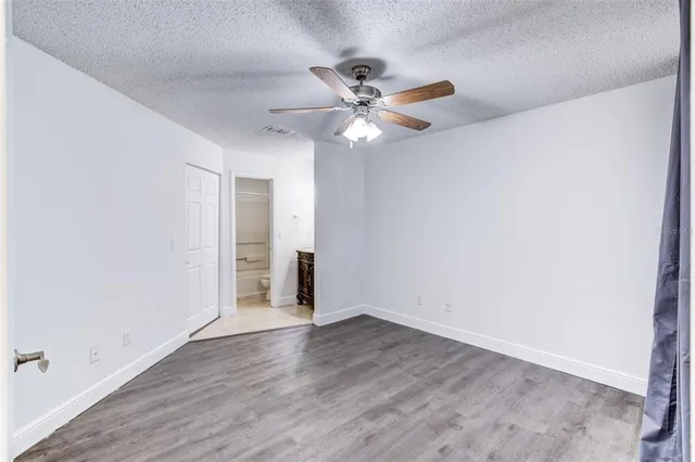 an empty room with wooden floor fan and windows