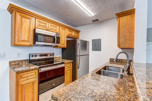 a kitchen with stainless steel appliances granite countertop a stove sink microwave and refrigerator