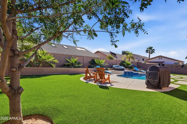 a view of a backyard with couches table and chairs under an umbrella