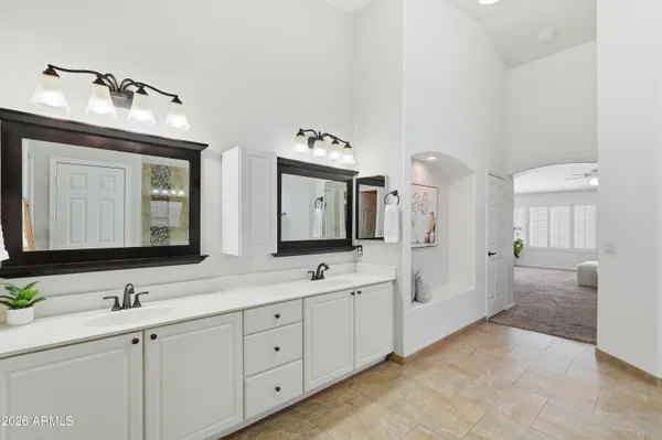 a spacious bathroom with double vanity a mirror and a shower