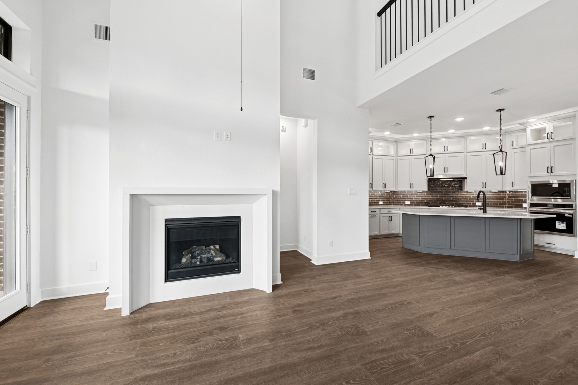 8731 Mancos Valley Porter, TX 77365 - Photo 26 of 46 a open kitchen with kitchen island a fireplace wooden floor and a refrigerator