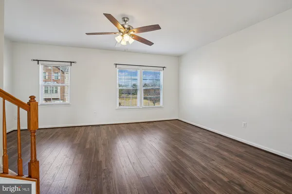 a view of an empty room with wooden floor and a ceiling fan