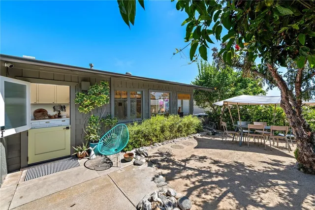 a view of a patio with table and chairs under an umbrella with potted plants