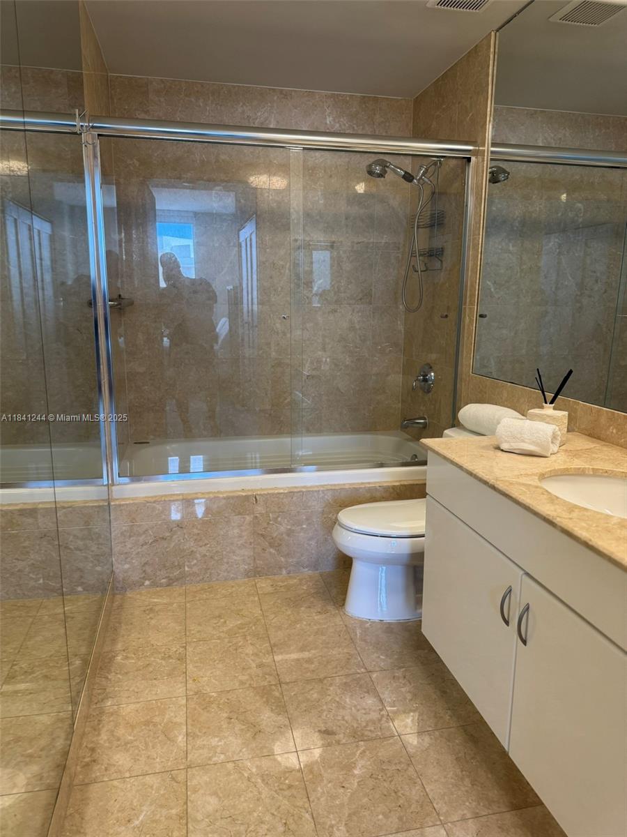 801 Brickell Key Boulevard, Unit 2705 Miami, FL 33131 - Photo 14 of 14 a bathroom with a granite countertop sink a toilet and shower