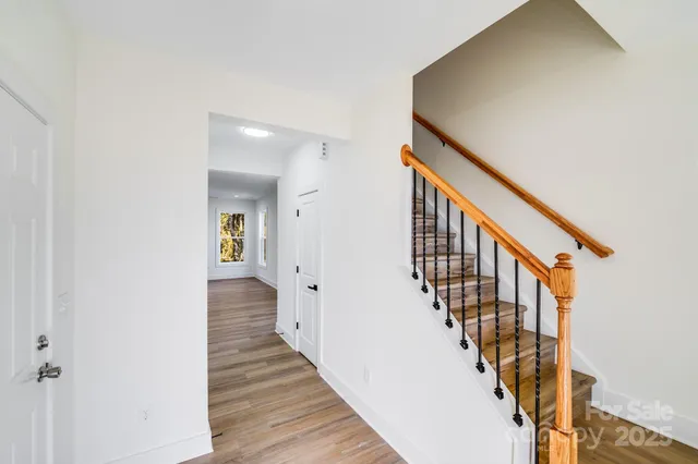 a view of a hallway with wooden floor and staircase