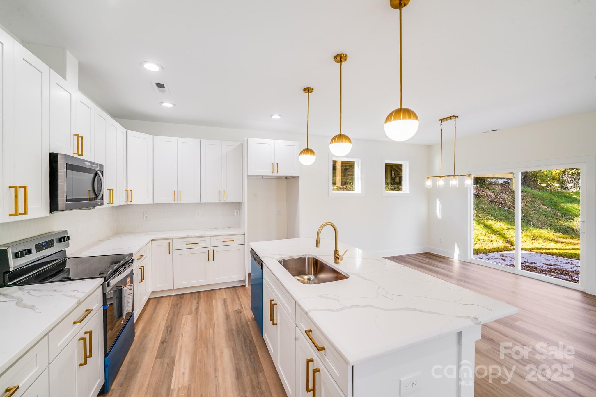 4538 Orphanage Road Concord, NC 28027 - Photo 5 of 14 a kitchen with a sink a stove and a wooden floor