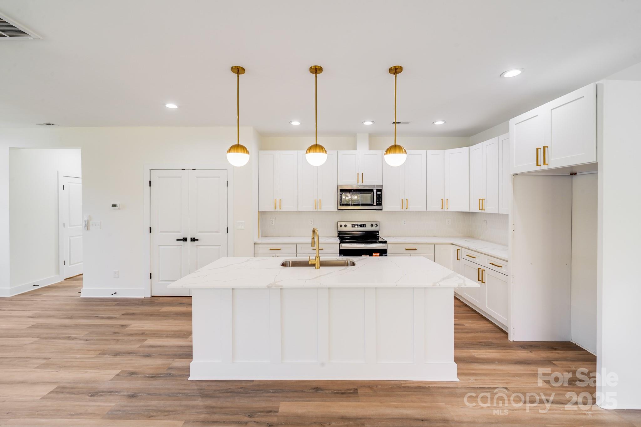 4538 Orphanage Road Concord, NC 28027 - Photo 6 of 14 a large kitchen with stainless steel appliances kitchen island granite countertop a refrigerator a stove and white cabinets with wooden floor