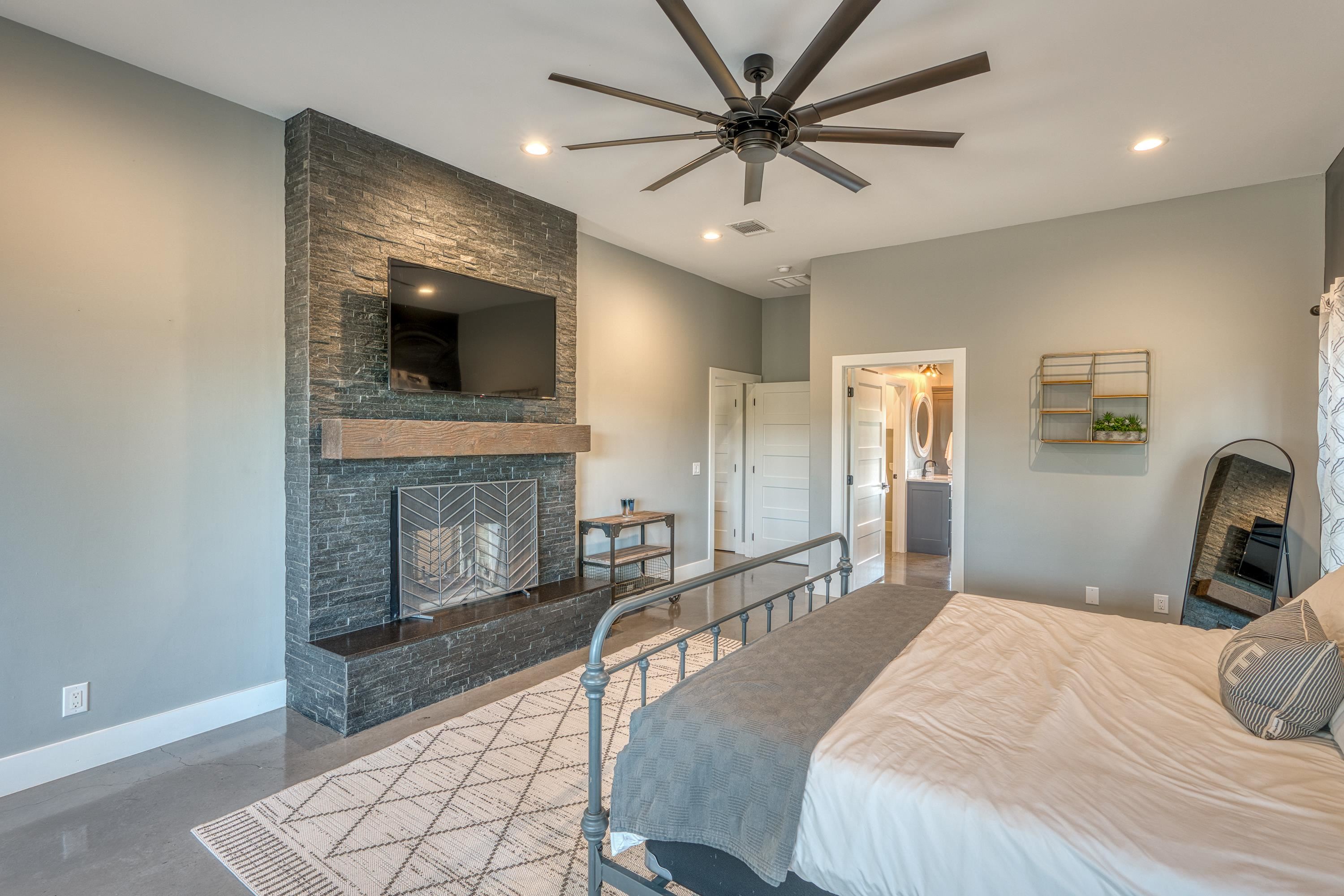 105 Keystone Buchanan Dam, TX 78609 - Photo 16 of 30 a bedroom with a large bed a flat tv screen and a fireplace