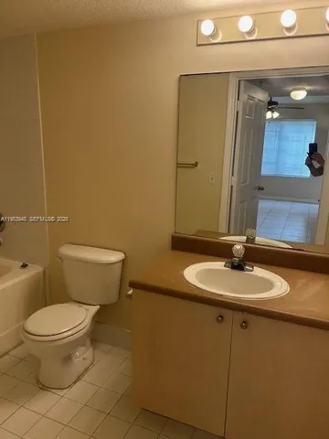 a bathroom with a granite countertop toilet sink and mirror