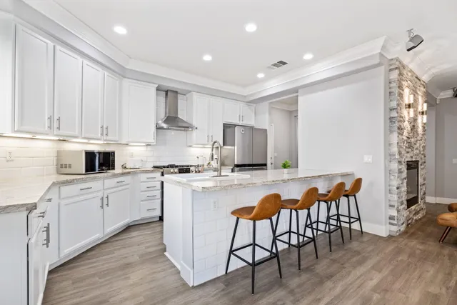 a kitchen with stainless steel appliances granite countertop a table chairs sink and cabinets