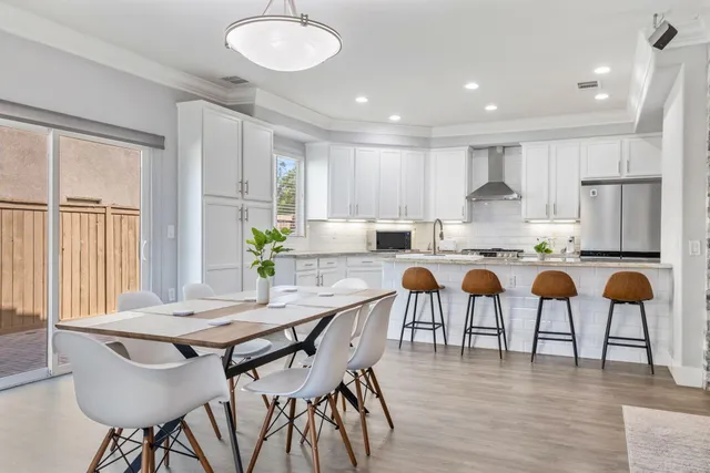 a kitchen with stainless steel appliances granite countertop a table chairs and a refrigerator