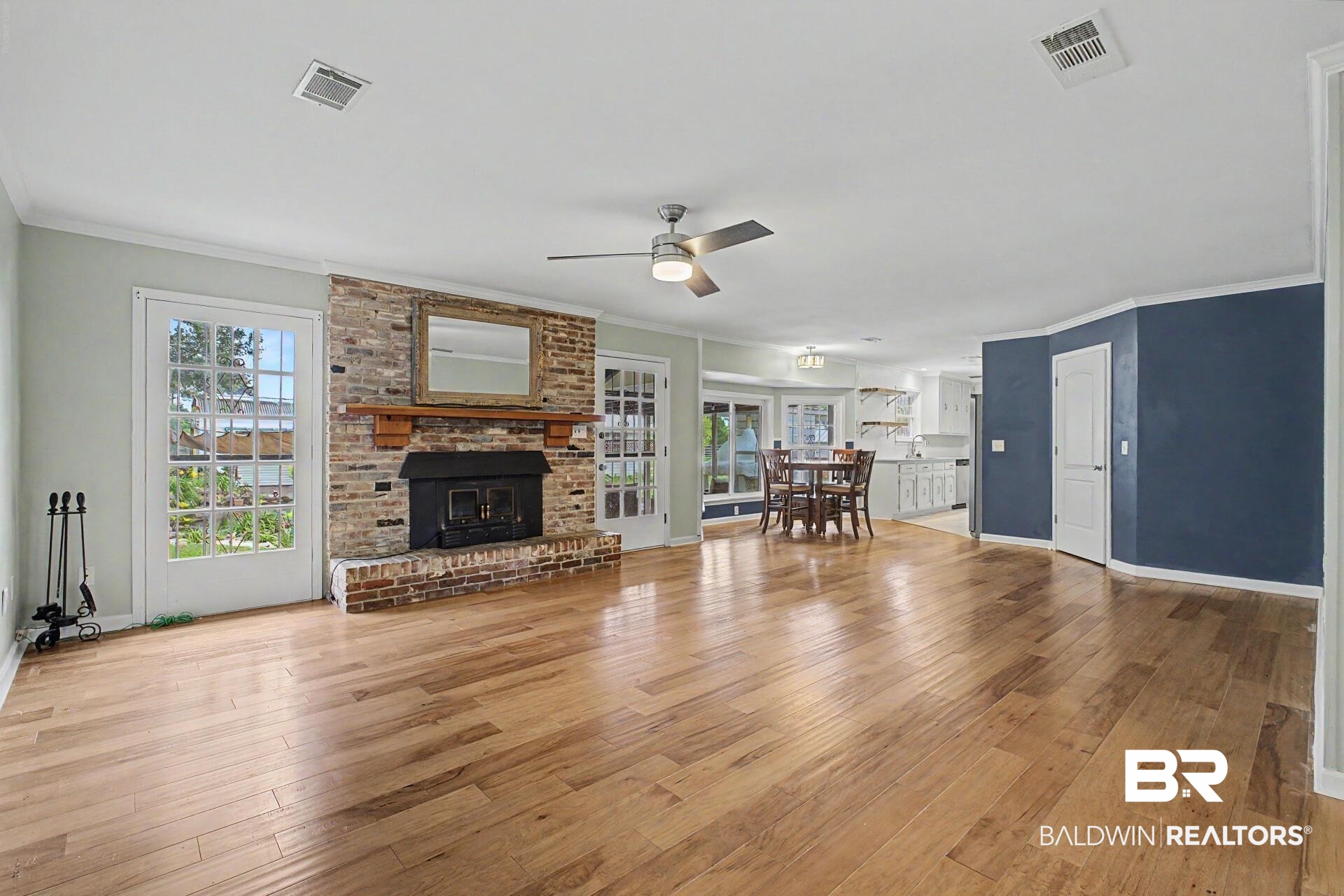 3791 Robinsonville Road Atmore, AL 36502 - Photo 32 of 47 Spacious living area featuring wood-finish flooring, a brick fireplace with a wood mantle, and two sets of French doors