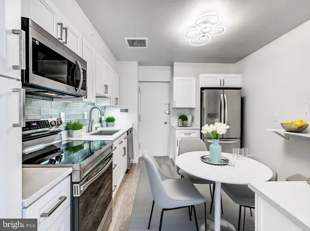 a kitchen with stainless steel appliances granite countertop a sink a stove a microwave a refrigerator and chairs