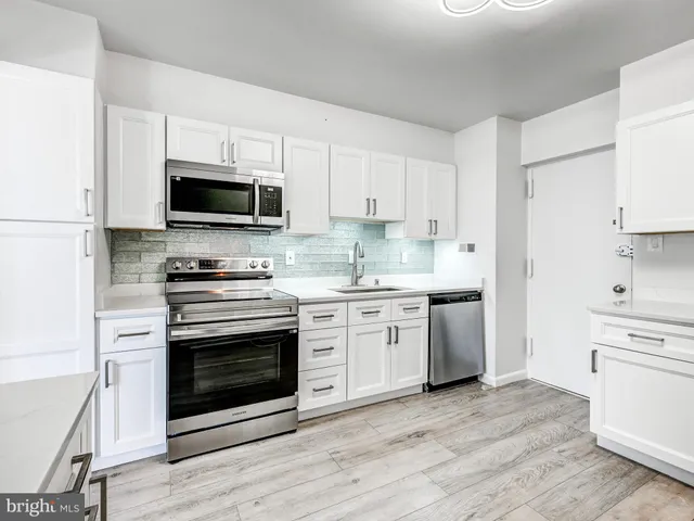 a kitchen with granite countertop a stove a microwave a sink and cabinets