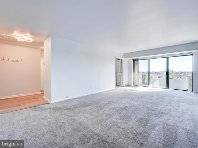 a view of empty room with wooden floor and window