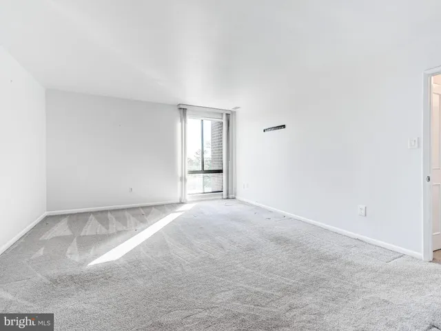 a view of an empty room with window and a livingroom