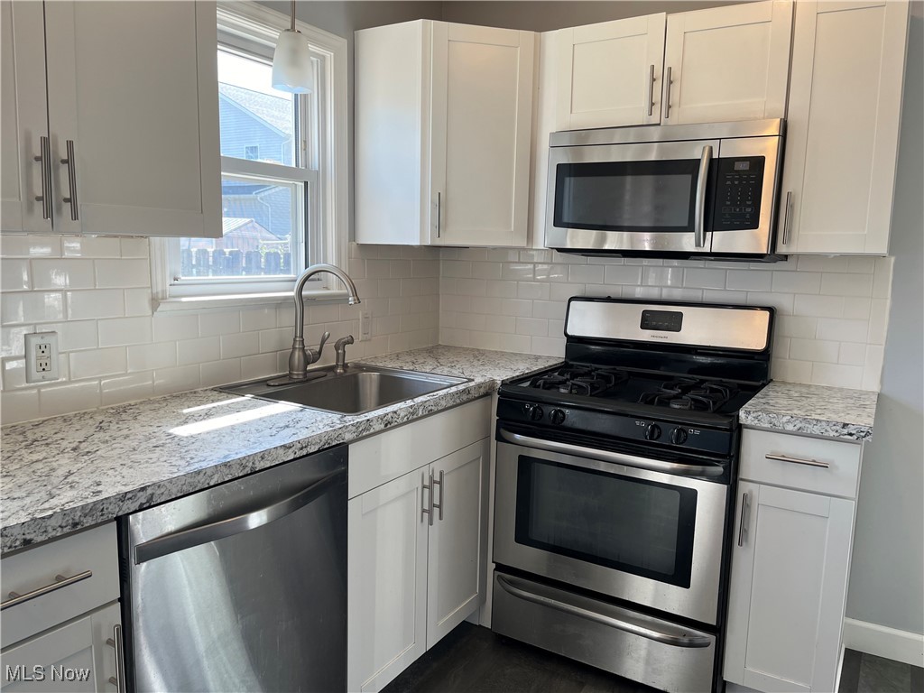29946 Enid Road Wickliffe, OH 44092 - Photo 21 of 50 Kitchen featuring white cabinets, stainless steel appliances, and decorative backsplash