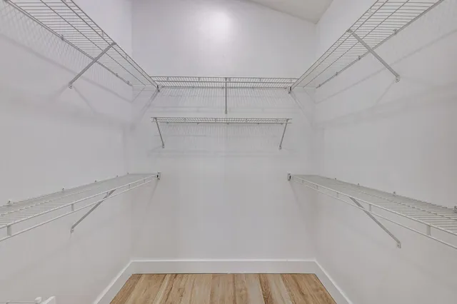 a view of a hallway with wooden floor and a bathroom