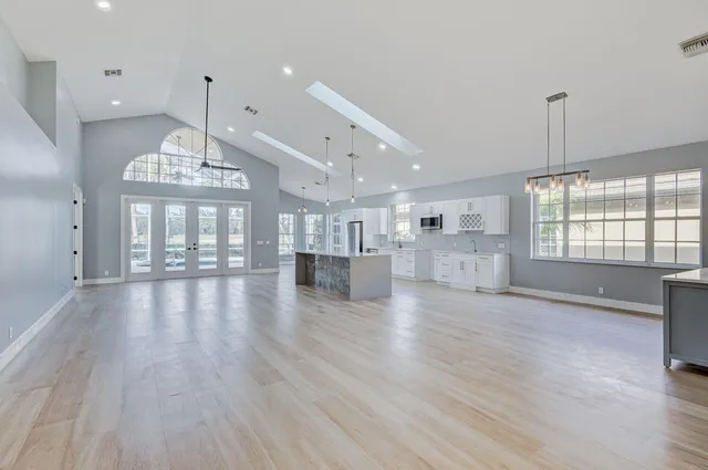 a kitchen with stainless steel appliances kitchen island granite countertop a stove a sink a refrigerator and white cabinets with wooden floor