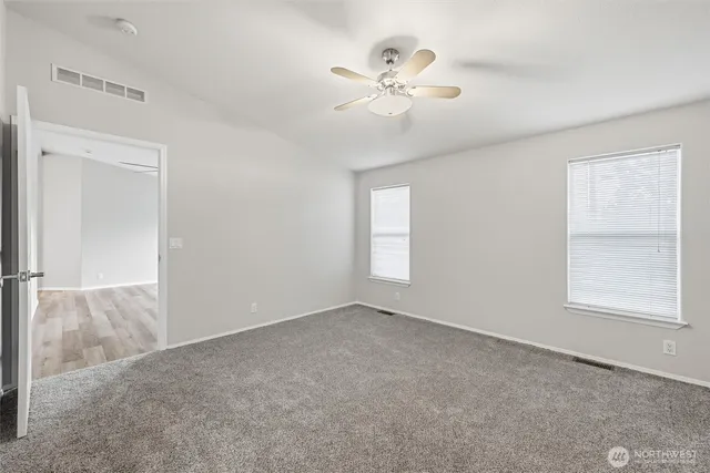 an empty room with windows and fan
