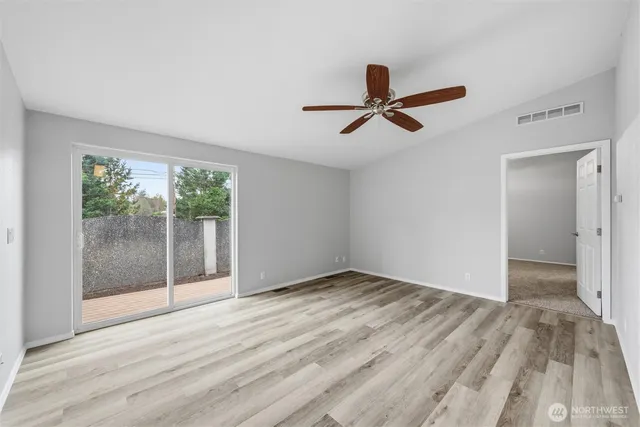 a view of empty room with wooden floor and fan