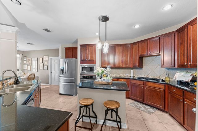 a kitchen with refrigerator a sink and chairs