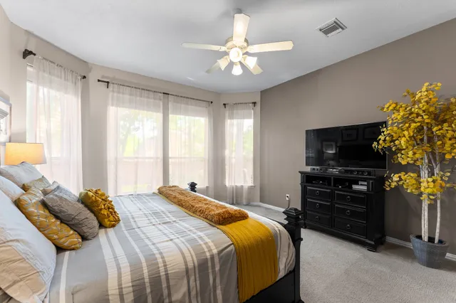 a bedroom with a bed and a flat tv screen on dresser