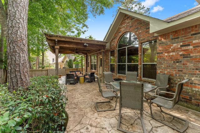 a view of a patio with table and chairs potted plants and large tree