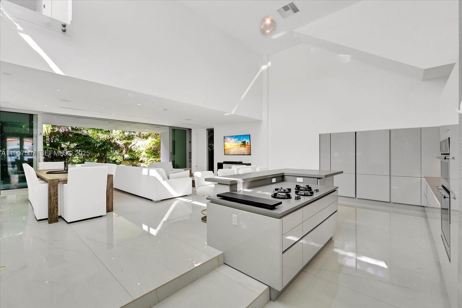 7830 Atlantic Way Miami Beach, FL 33141 - Photo 5 of 34 a kitchen with a counter top space a sink a refrigerator a window and a couch