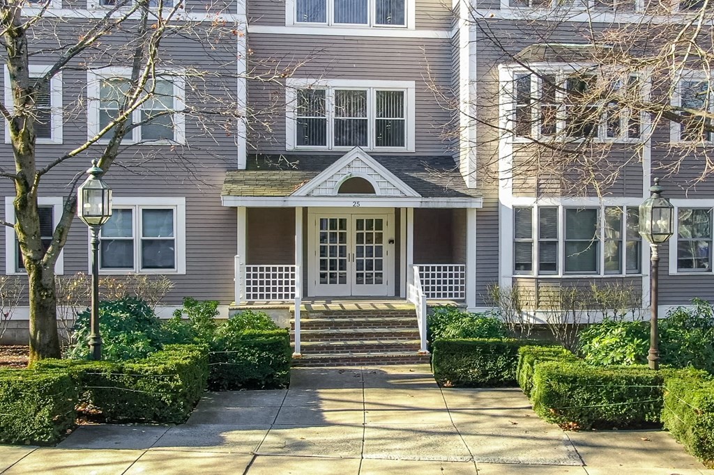 25 Holly Lane, Unit 2A Brookline, MA 02467 - Photo 30 of 34 a front view of a house with a yard and potted plants