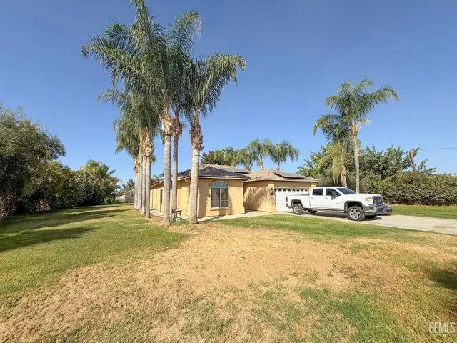 a view of a house with a yard and palm trees